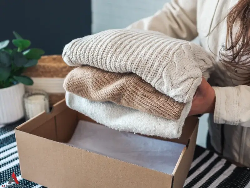 Woman placing folded sweaters in box for bed bug control service page in Huntersville, NC
