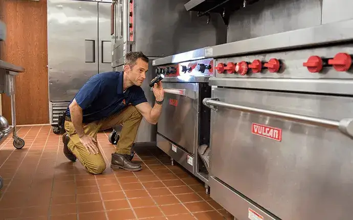 Man inspects a commercial kitchen, highlighting the need for commercial pest control in Lenoir.