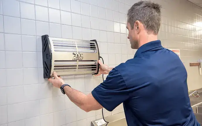 Man installs device, highlighting the need for Hickory commercial pest control.