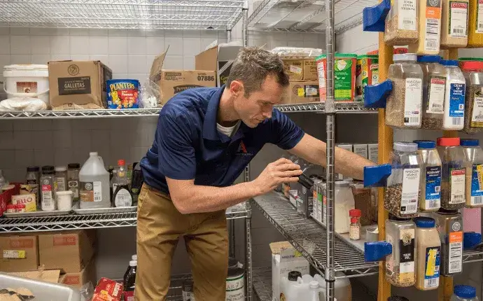 Man inspects food containers, highlighting the need for commercial pest control in Hickory, NC.