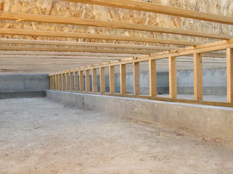 The framing of the underside of a house, highlighting the need for crawl space encapsulation in Mooresville, NC.